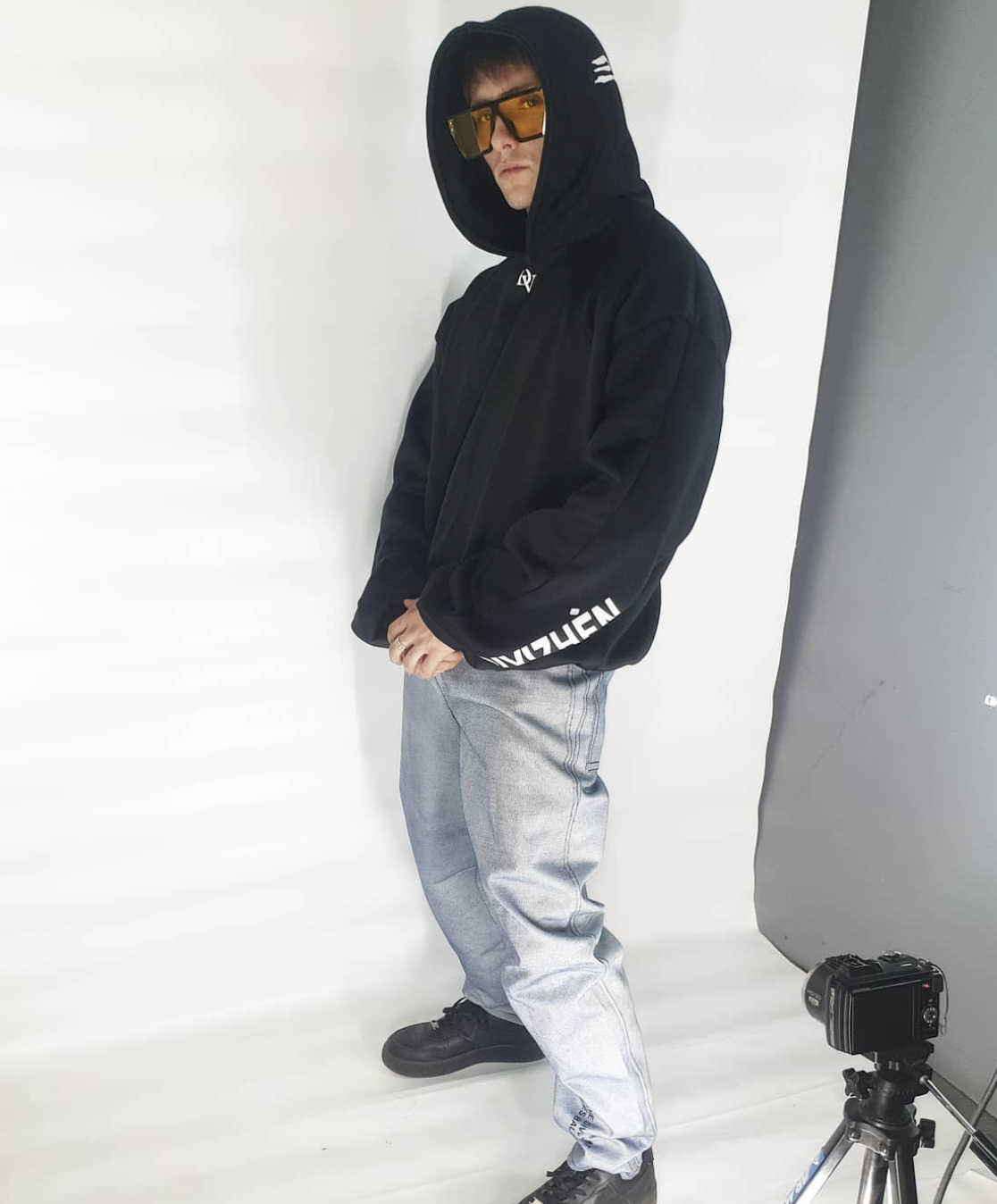 Hayden Bouwer, founder of DIVIZHÈN, wearing the black hooded sweatshirt in studio
